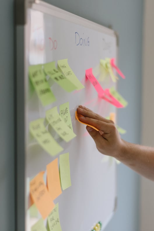 Person Sticking Colorful Sticky Notes on Whiteboard